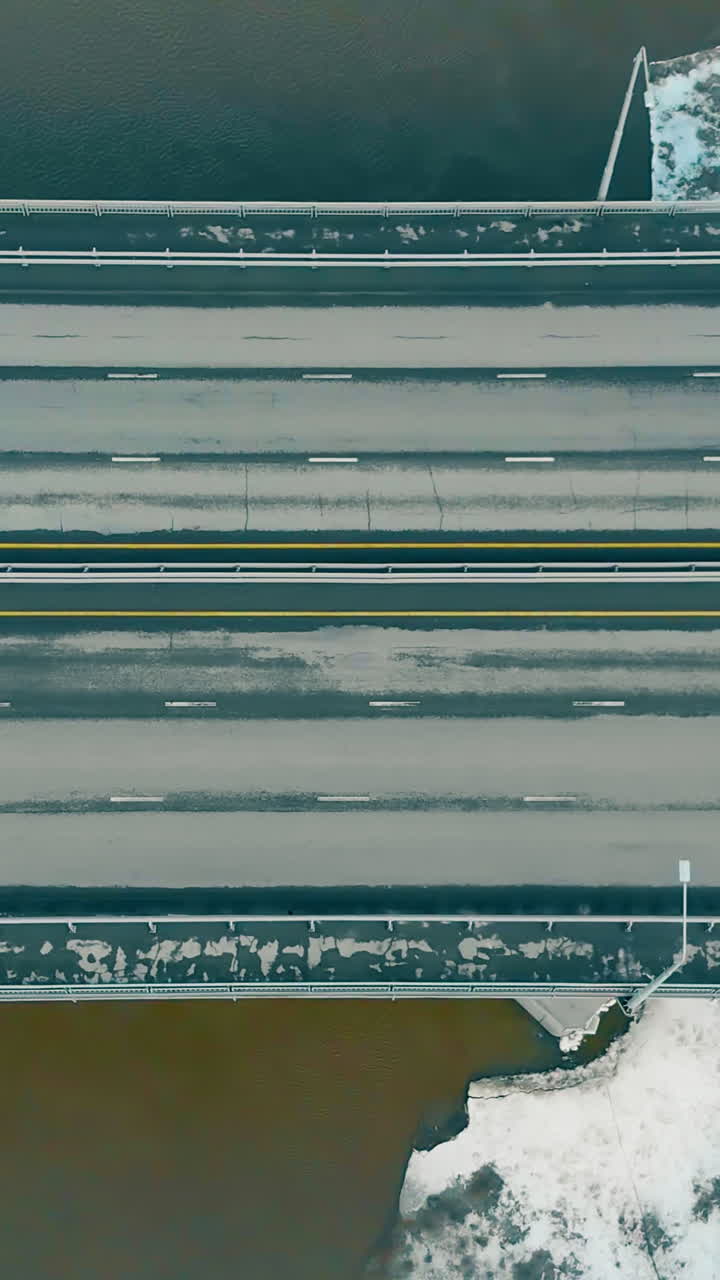 brown dirty river water covered with melting ice surface with ridges under tremendous highway bridge upper view