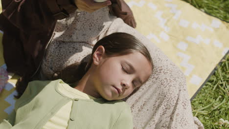 girl sleeping on a blanket while someone reads to her