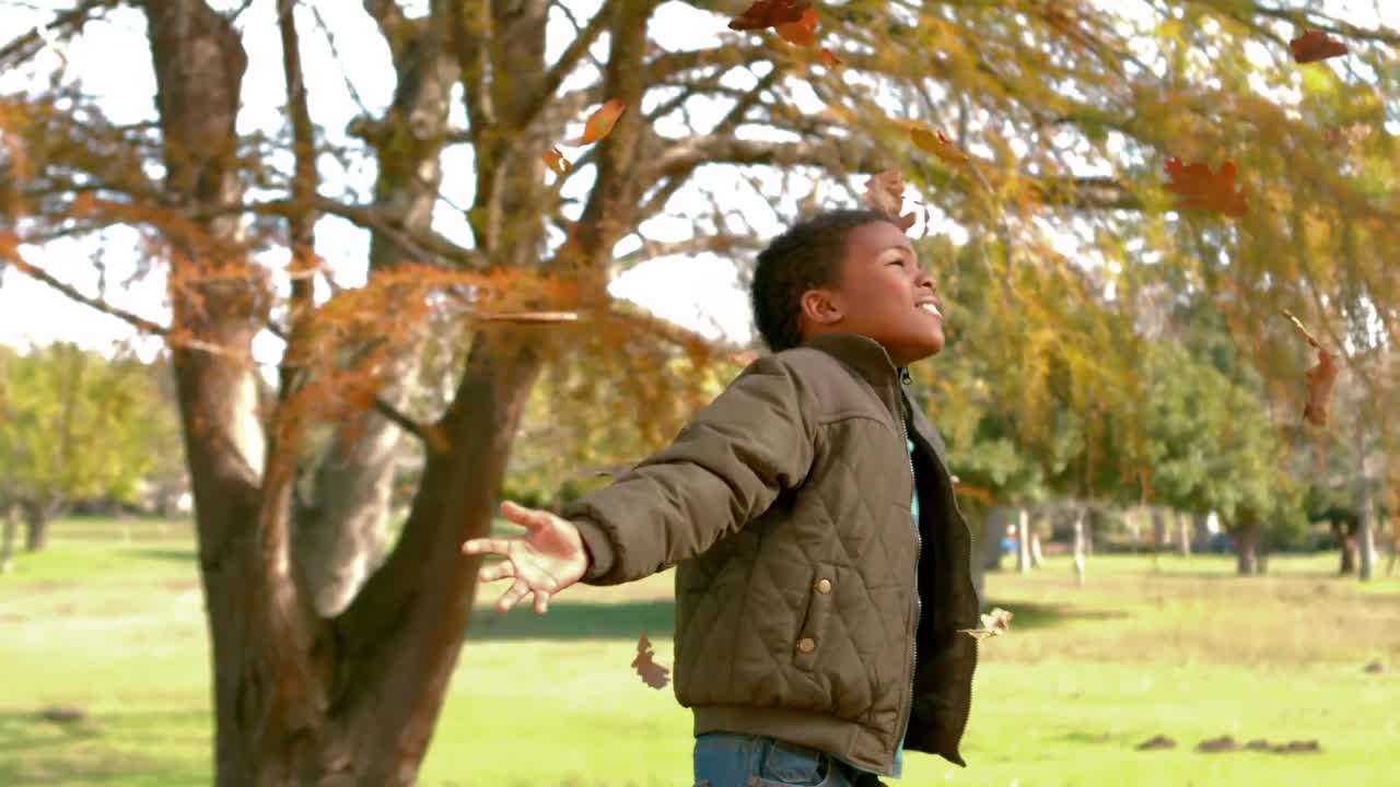 niño feliz lanzando hojas por ahí