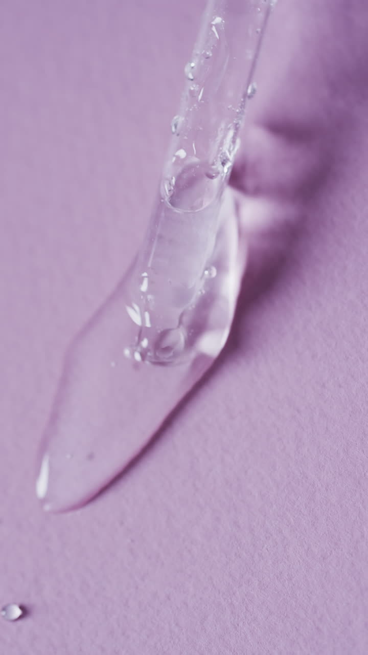 Video verticale di pipetta per trucco e gocce di siero con spazio per il testo su sfondo rosa