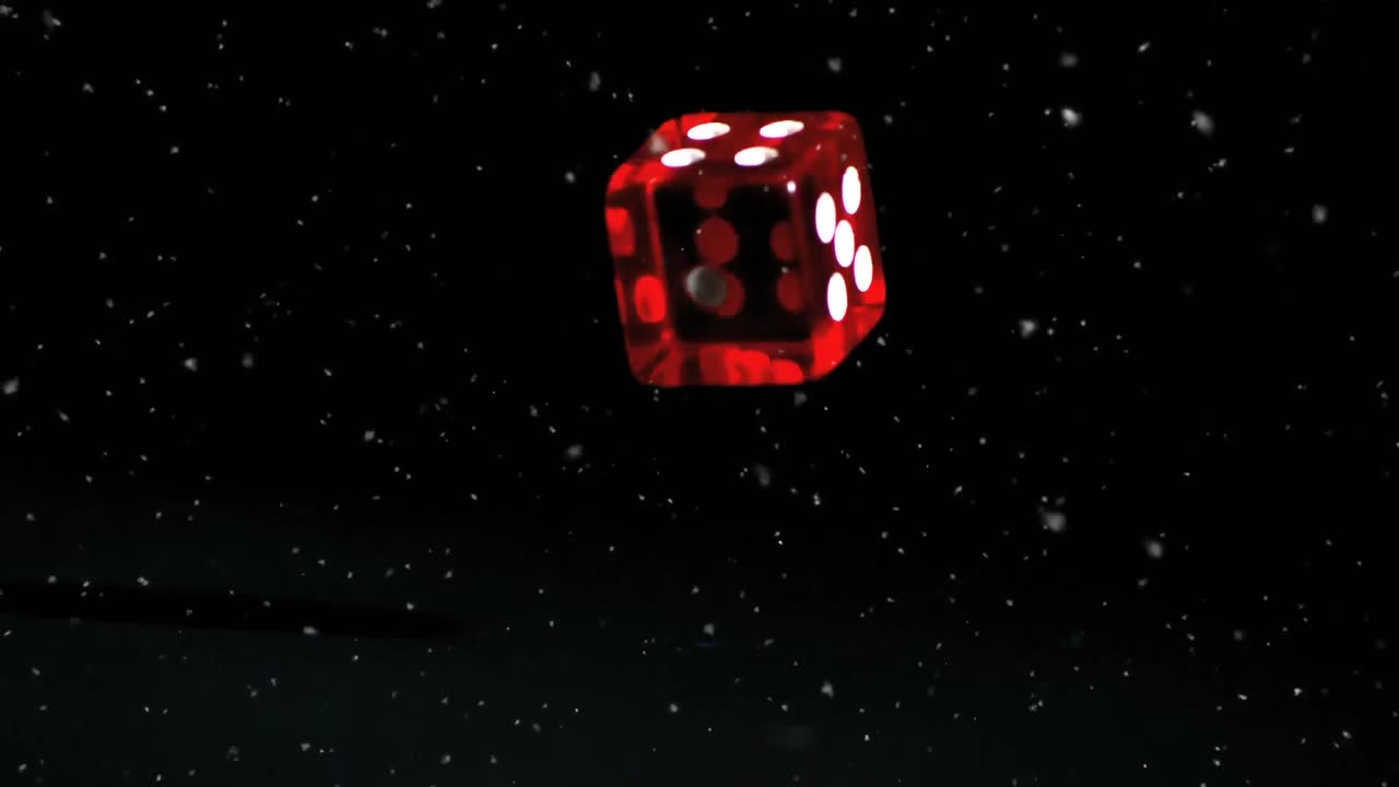 partículas blancas flotando sobre los dados rojos del casino cayendo contra un fondo negro
