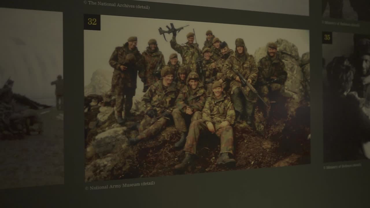 Vintage military archive photograph displaying soldiers posing together outdoors, projected on museum screen representing historical military documentation