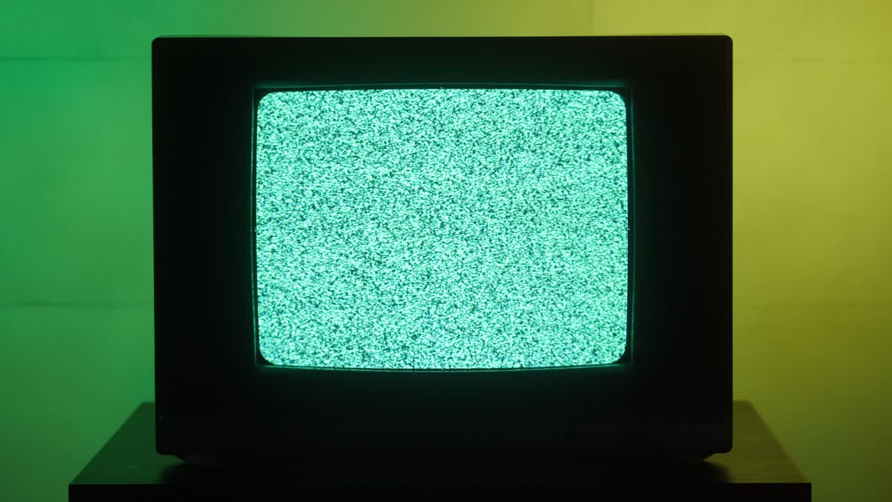 Old retro square television on green and yellow neon background, screen with ripples and interference. Old-fashioned TV with bad signal reception, tv setting concept, searching channel