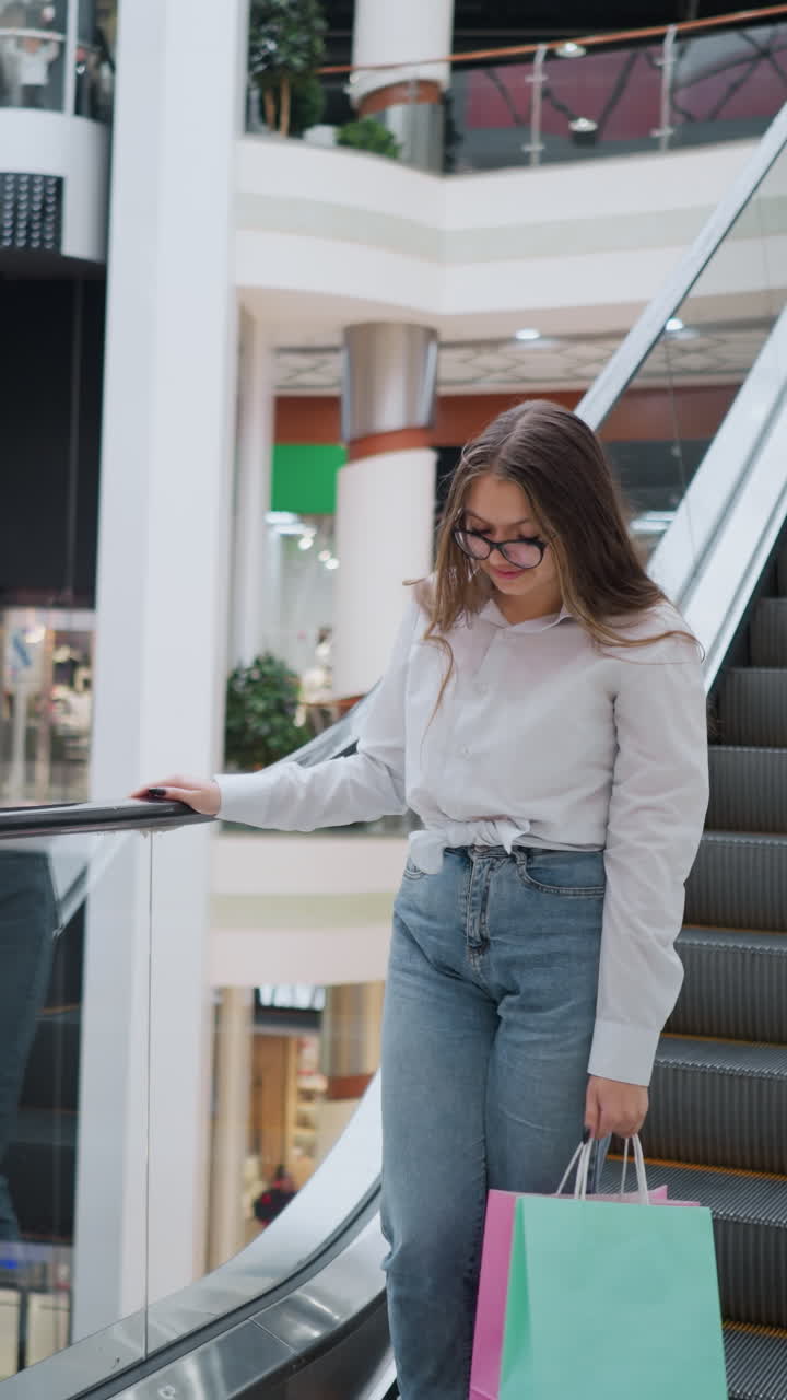 una mujer baja de la escalera mecánica con bolsas de compras en la mano en un bullicioso centro comercial moderno, rodeada de diversas tiendas y compradores en el fondo, reflejando el vibrante estilo de vida del consumidor urbano