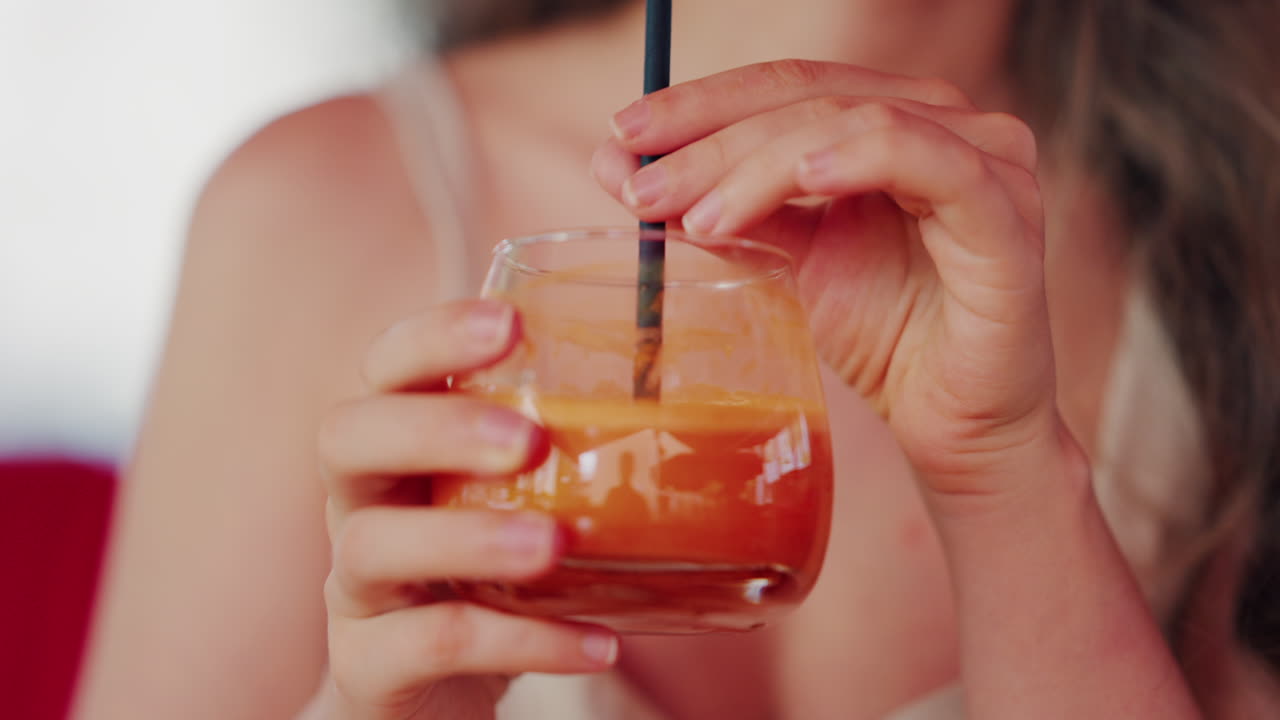 Close up of a woman sipping fresh carrot juice through a straw