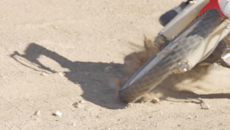 slow motion: a dirt biker rides his crf honda through the desert and whips around a berm