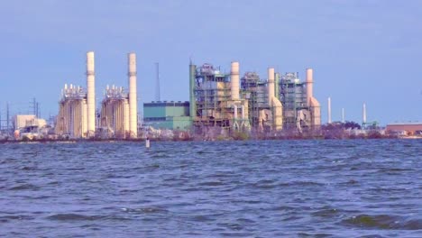 view of a power station from across a rough lake with waves created by the wind