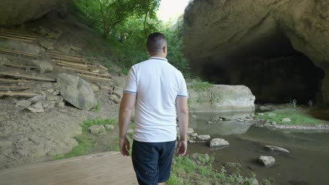 a man is walking towards god's bridge, a natural stone arches near vratsa in bulgaria