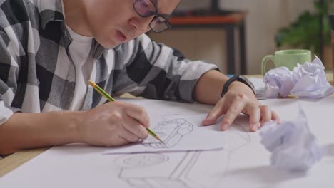 close up of asian male crumpling paper while working on a car design sketch on table in the studio