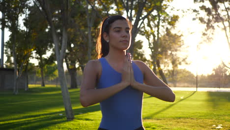 una bonita mujer hispana en una pose de yoga de manos de oración meditando en el parque al amanecer