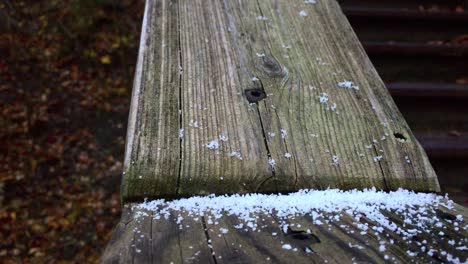 outdoor close up on an old weathered wooden stairwell surface showing first snowfall of the season