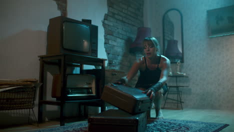 woman searching a vintage suitcase in a retro room