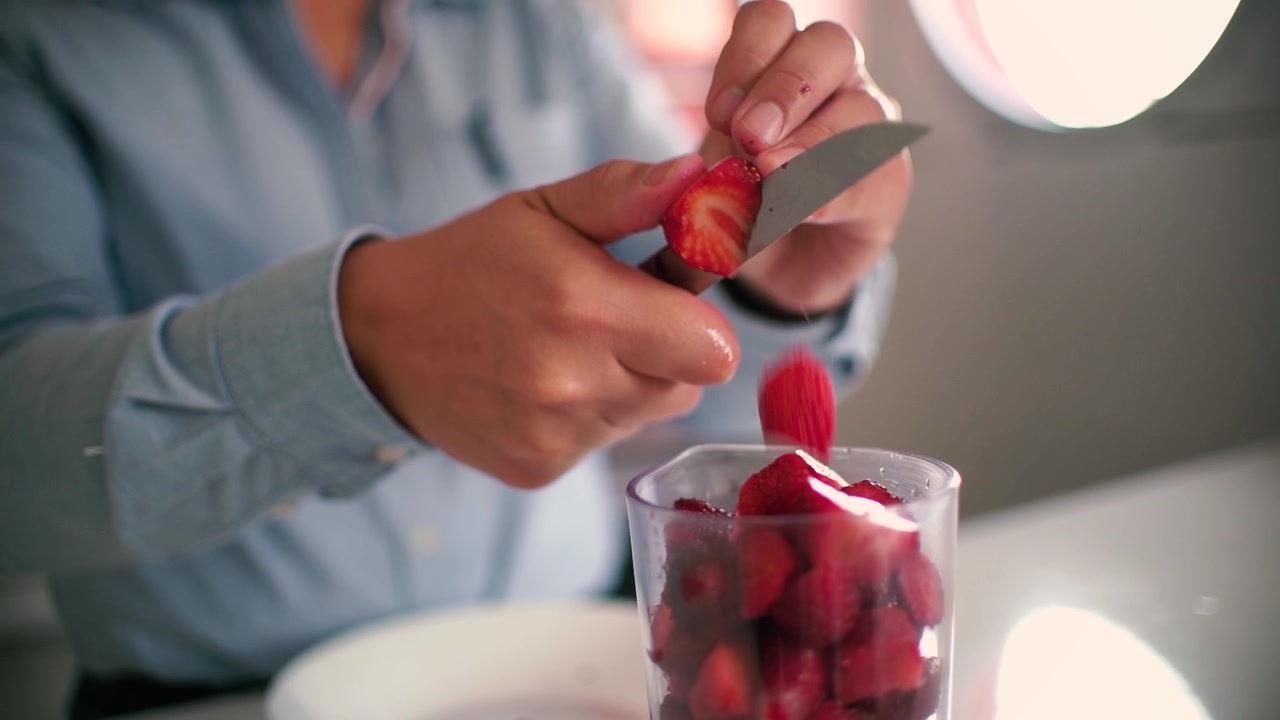 Woman's hands slicing strawberries cooking, cutting fruits in half. Cuisine at home kitchen.