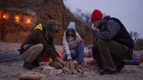 friends enjoying a campfire on the beach in winter