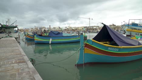 traditional maltese fishing boats rocking on surface of water in marsaxlokk bay in winter