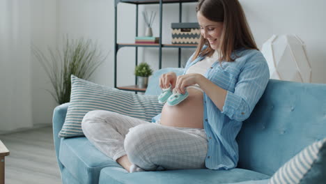 pregnant woman putting baby shoes on her belly