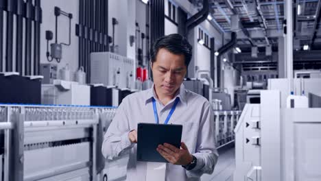 asian male professional worker standing with his tablet with water production in bottling factory, work continuously with his tablet
