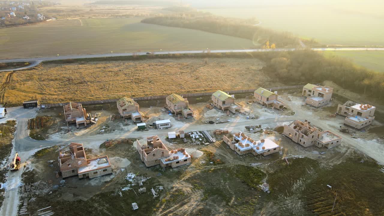 Vista aerea di nuove case con muri con struttura in mattoni in costruzione in una zona suburbana rurale. Sviluppo immobiliare nelle moderne periferie cittadine
