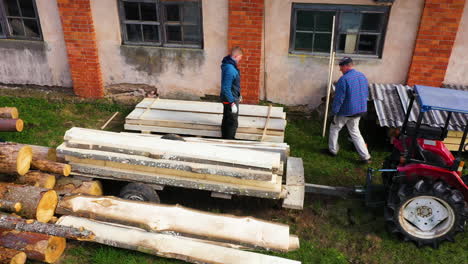 two men working with logs and lumber in an outdoor setting