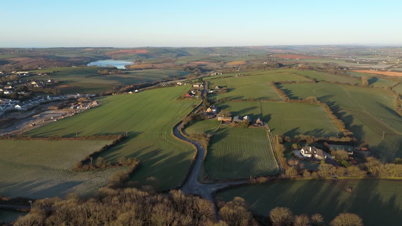 A stunning morning light, lush green landscapes of Kinsale, Ireland, casting long shadows over the suburban hedgerows. Drone flight in golden hour above coastal town.