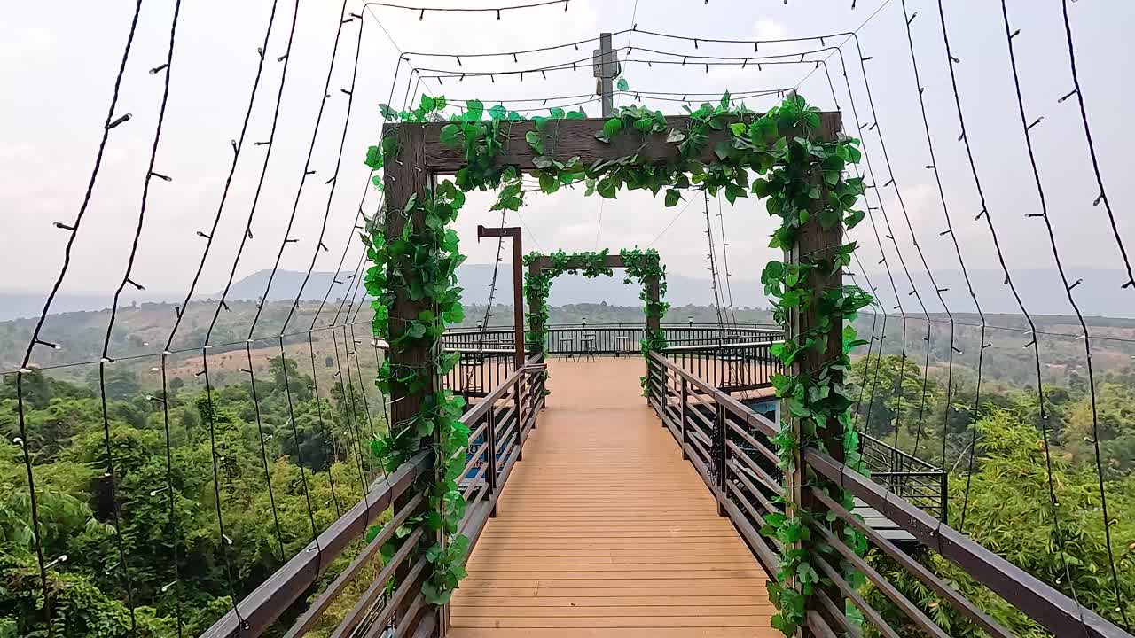 Aerial view of a skywalk with lush greenery and expansive vistas in Champasak, Laos. Bright daylight enhances the serene atmosphere