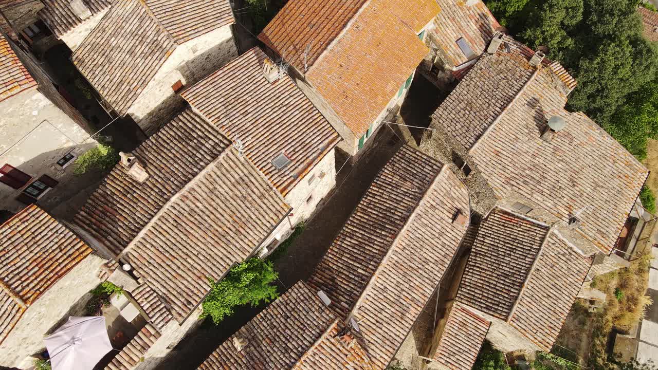 Tiled rooftops of Baschi glow under sun as drone moves smoothly over old alleys