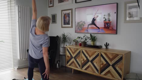 video de una mujer mayor activa haciendo ejercicio frente a la televisión
