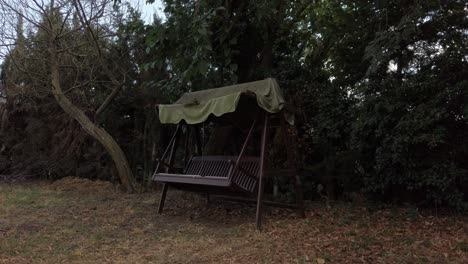 an empty swinging bench moves gently in the breeze