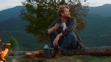 Joyful-hiker-relax-bonfire-in-mountains.-Close-up-camper-enjoy-drink-outside.