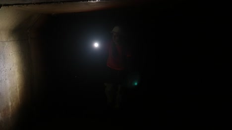 person with flashlight in a dark tunnel