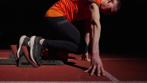 sprinter in starting blocks at night