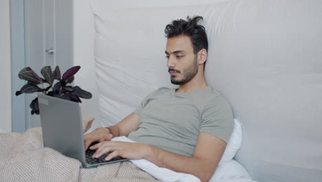 hombre trabajando en la computadora portátil en la cama