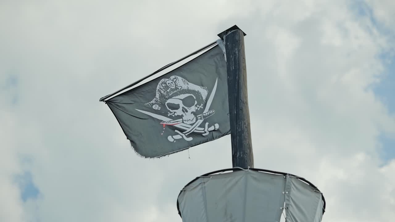 Black pirate flag flutters in cloudy sky reflecting rebellion and timeless myth