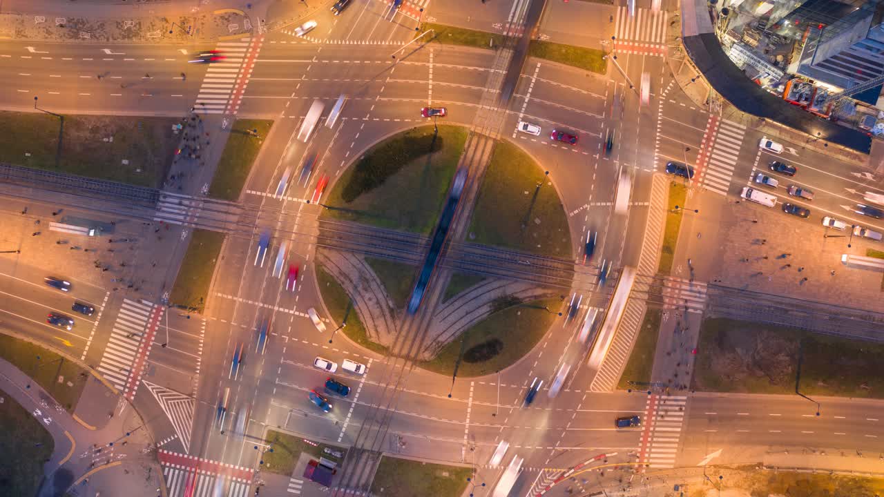 Top-down nighttime view at a huge roundabout in Warsaw, Poland. Lots of traffic, pedestrians. Video with camera motion.