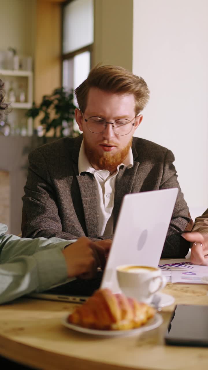 Due uomini che discutono di affari davanti a un laptop e un caffè al bar