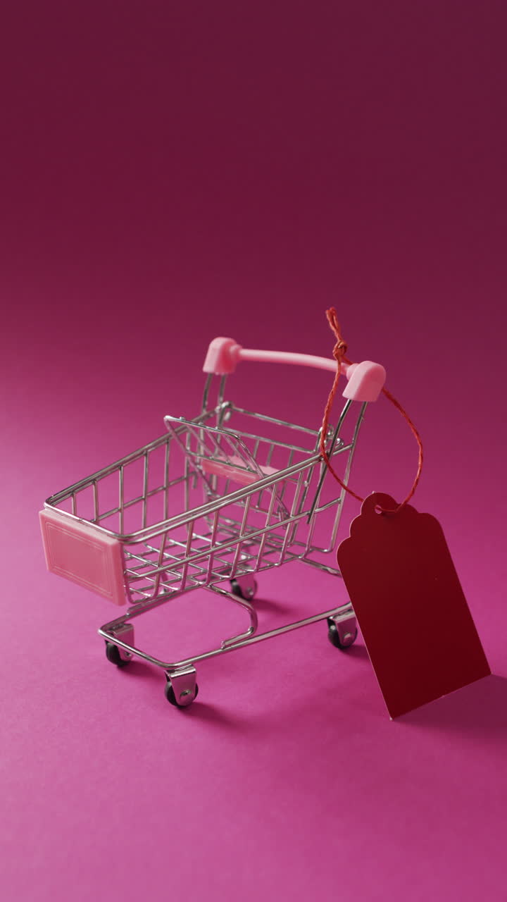 video vertical del carrito de compras con etiqueta de regalo en fondo rosa