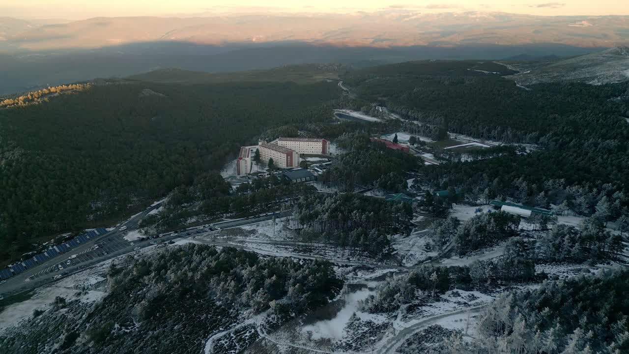 toma aérea volando sobre un bosque nevado con caminos y carreteras y algunos edificios en un puerto de montaña en manzaneda, galicia