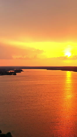 evening view on the factory with pipes near the river. natural scenery of the river at sunset. golden path over the water surface. air pollution in the environment. vertical video