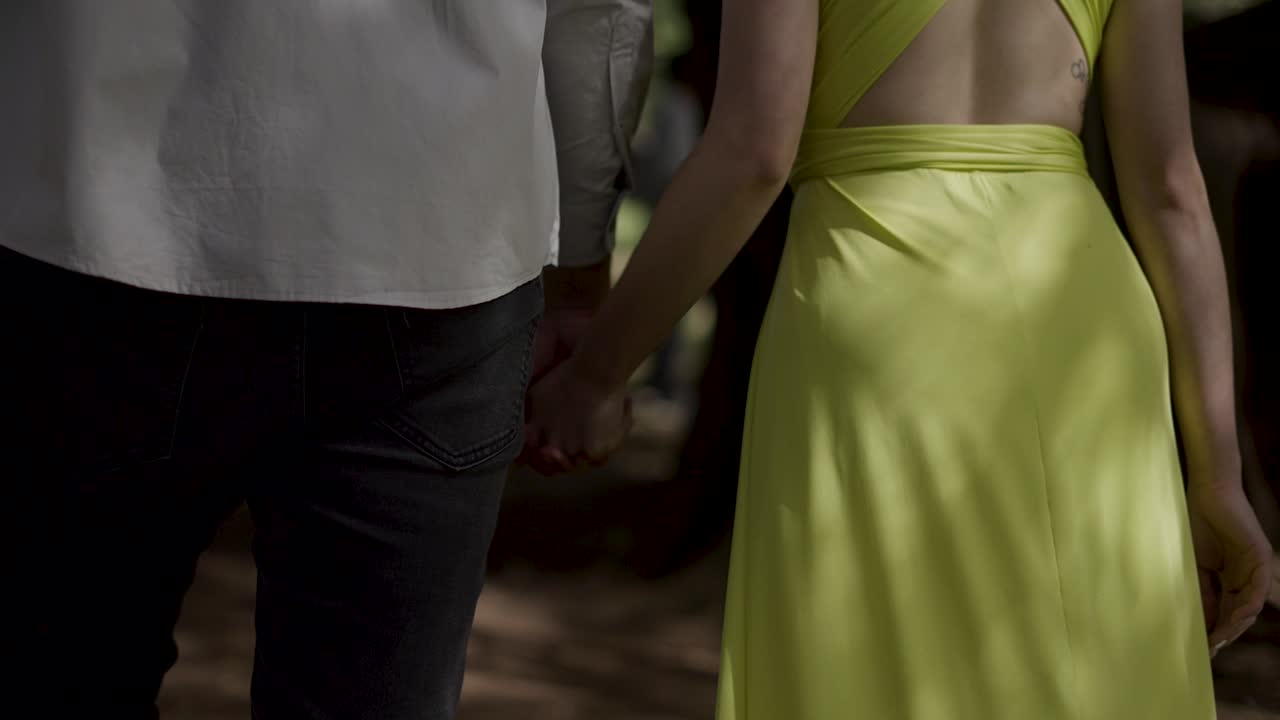 couple holding hands walking in the forest