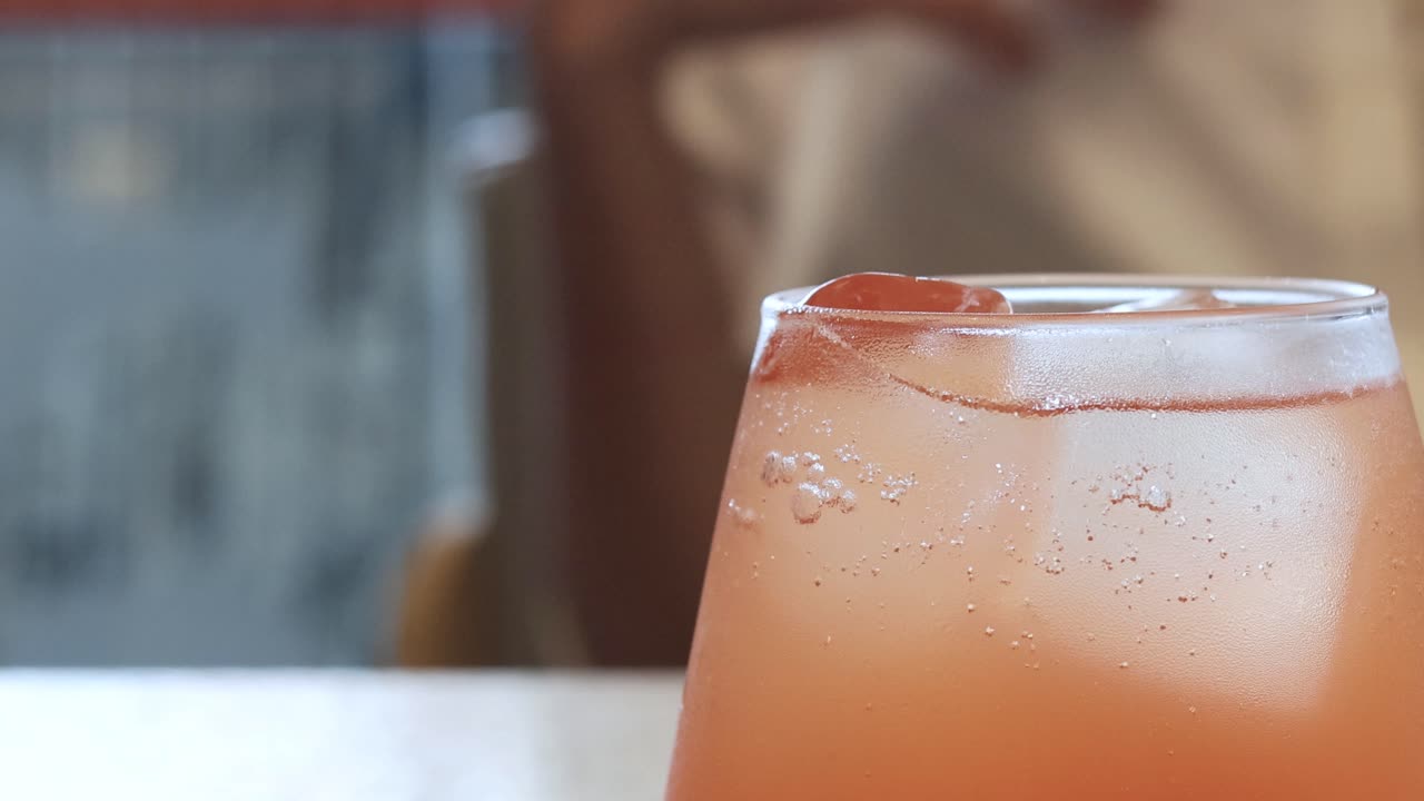 Una persona beve una bevanda fredda e arancione
