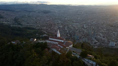 drone orbits bogotá’s cerro de monserrate, iconic religious site and lush surroundings overlooking the city in colombia at sunset