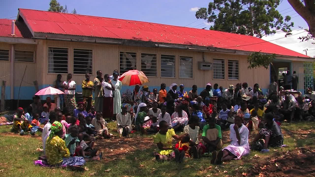 Eine Gruppe Afrikaner sitzt im Schatten vor einem Gebäude.