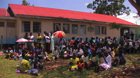 a group of africans sit in the shade in front of a building