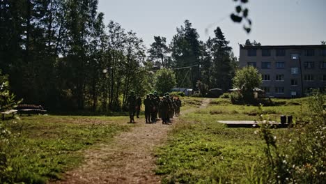 Jóvenes-Soldados-Del-Ejército-Marchando-En-El-Bosque-Con-Boina-Verde-En-Camuflaje-Militar-Con-Un-Edificio