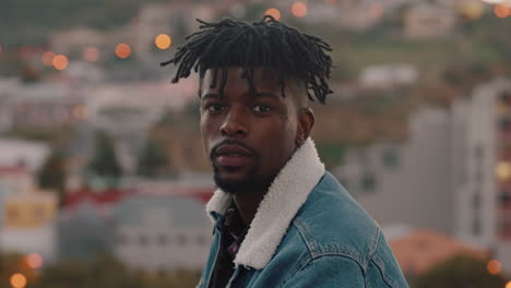 portrait attractive young african american man smiling confidently enjoying successful lifestyle on rooftop in city skyline at sunset