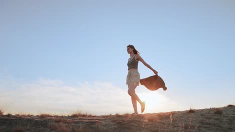Free woman walking through desert sand dunes at sunset, cinematic slow motion