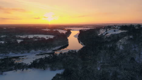 la vista aérea del bosque invernal cubierto de nieve a tiempo al atardecer en vísperas de navidad.