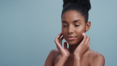 slow motion portrait beautiful african american woman feathers falling on smooth skin touching bare shoulders enjoying natural skincare beauty gently caressing body in blue background