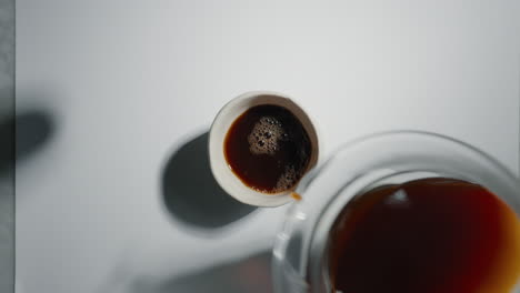 home barista pouring coffee into cup from glass carafe