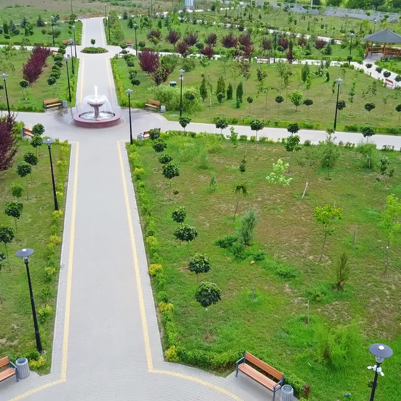 Paved paths in the newly created park with young trees. Garden for rest and walk in the city. Top view